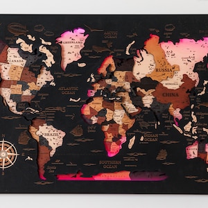 Peut inclure: Une carte du monde en bois avec les pays découpés, montée sur un fond noir. La carte est éclairée par des lumières roses et oranges, mettant en valeur les continents et les océans. Une rose des vents est dans le coin inférieur gauche.