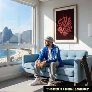 May include: A framed poster with the words "Fire Ball" in a stylized red font against a dark red background. The image also shows a person sitting on a blue couch, a skateboard, and a window with a view of a beach and mountains. *THIS ITEM IS A DIGITAL DOWNLOAD*