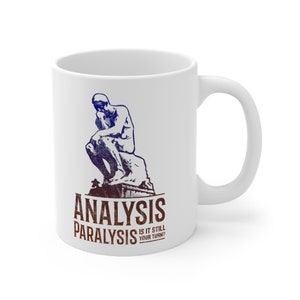 Pu&ograve; includere: Tazza in ceramica bianca con un'illustrazione blu e bianca della statua del Pensatore. Il testo "Analysis Paralysis Is It Still Your Turn?" &egrave; stampato in marrone e bianco sotto l'illustrazione.