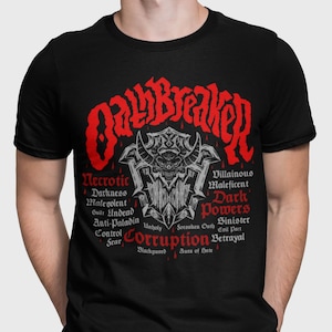 Peut inclure: T-shirt noir avec un motif rouge d'un crâne avec des cornes et le texte "Oathbreaker" au-dessus. Le motif est entouré de texte qui dit "Necrotic, Darkness, Malevolent, Guilt Undead, Anti-Paladin, Control, Fear, Unholy, Corruption, Blackguard, Aura of Hate, Villainous, Maleficent, Dark Powers, Soronken Oath, Sinister, Evil Part, Betrayal".