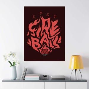 以下が含まれることがあります： 「CAST FIRE BALL」の文字が炎のデザインで描かれた赤と黒のポスター。炎の下部には赤とグレーのD20サイコロがあります。ポスターは白い壁に飾られています。