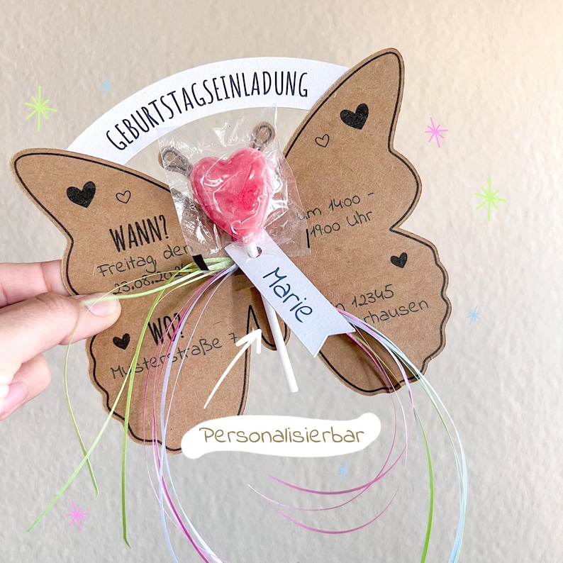 May include: A brown butterfly-shaped card with a lollipop attached to it. The card has the text "Geburtstagseinladung" (Birthday Invitation) and "WANN?" (When?) with a date and time. The card also has the text "WO?" (Where?) with an address. The lollipop is a red heart-shaped lollipop. The card is decorated with hearts and stars. The text "Personalisierbar" (Personalizable) is written on the card.