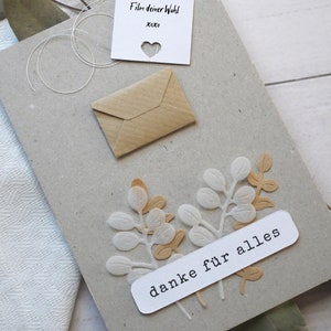 May include: A handmade greeting card with a kraft paper envelope and a small white card with a heart cutout. The card features decorative leaf cutouts and the words "danke f&uuml;r alles".