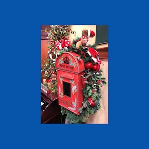 May include: A red vintage post office box decorated for Christmas. The box is adorned with holly, ornaments, and a Santa Claus figure. The words "Post Office Letters" and "Santa" are visible on the box.