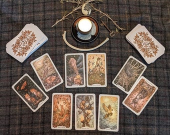 May include: A spread of tarot cards on a plaid fabric surface. The cards feature illustrations of animals and nature scenes. A candle and a bone are also visible in the image.