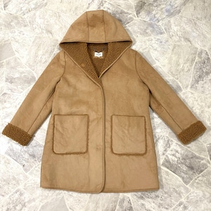 May include: A tan hooded coat with a faux suede exterior and a brown sherpa lining. The coat features two front pockets, a button closure, and sherpa trim on the cuffs. The coat is laid flat on a stone surface.