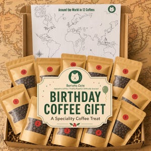 May include: A cardboard box containing twelve small brown pouches filled with coffee beans, each labelled with a red numbered sticker. A white card features a world map titled Around the World in 12 Coffees and a Barista Cats Birthday Coffee Gift sign.
