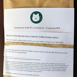 A brown paper coffee bag with a white label featuring a green circular logo of a cat face. The label includes the text Guatemala SHB EP La Pastora - Fraijanes RFA and information about a Barista Cats 3 Month Coffee Subscription.