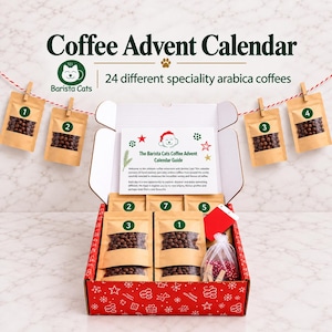 May include: A Coffee Advent Calendar box by Barista Cats containing 24 speciality arabica coffees in brown pouches. The set includes a guide, a red tag, a small white organza bag with red and white twine, and wooden clips for hanging the numbered pouches.