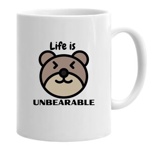 May include: White ceramic mug with a brown cartoon bear face and the text "Life is Unbearable".