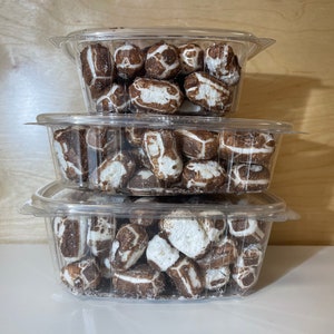 May include: Three clear plastic containers stacked on top of each other, filled with chocolate-covered sweets. The sweets are white and brown and have a slightly irregular shape.