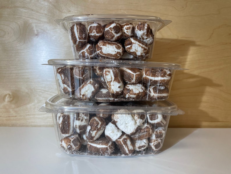 May include: Three clear plastic containers stacked on top of each other, filled with chocolate-covered sweets. The sweets are white and brown and have a slightly irregular shape.