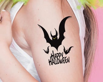 May include: A black temporary tattoo featuring a bat design with the text "Happy Halloween". The bat has large wings and glowing yellow eyes. The tattoo is applied to the upper arm.