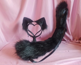 May include: Black faux fur cat ears headband and tail set. The headband has a heart-shaped metal frame. The tail is long and fluffy with a black ribbon.
