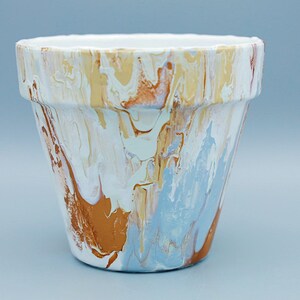 May include: A white terracotta planter with a marbled design in shades of blue, brown, and beige.