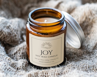 May include: A brown glass jar candle with a white label that reads "JOY SOY WAX CANDLE Net Wt. 000z | 000g | Atlanta, GA YOUR CANDLE CO.". The jar has a silver lid.