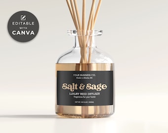Puede incluir: Botella difusora de caña de vidrio transparente con borde dorado y etiqueta negra. La etiqueta dice "Salt & Sage" y "Luxury Reed Diffuser". La botella contiene cañas de madera y está diseñada para la fragancia del hogar.