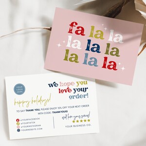 May include: Two holiday-themed cards. One pink card features the phrase "fa la la la" in red, green, blue, and white, with star accents. The second card is white with text in gold, red, and blue, including "happy holidays!" and "We hope you love your order!"