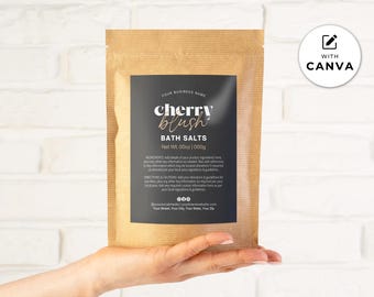 May include: A brown paper bag of bath salts is held. The bag features a black label with the words "cherry blush" in a script font. The label also includes "BATH SALTS" and "Net Wt. 00oz | 1000g". The background is a white brick wall. The bag weighs 1000g.