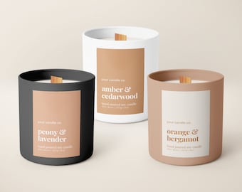 Puede incluir: Tres velas de soja en recipientes negros, blancos y marrones con mechas de madera. Las etiquetas son de color melocotón con texto blanco. Las velas están etiquetadas como "peonía y lavanda", "ámbar y madera de cedro" y "naranja y bergamota".