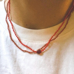 May include: A layered necklace with two strands of small red beads and a single red heart charm.