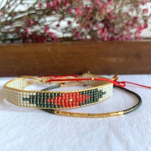 May include: Two beaded bracelets, one with a red and green geometric pattern and the other with gold beads.