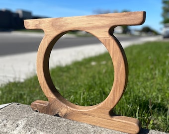 May include: A wooden ring with a large, circular opening. The ring is made of light brown wood and has a smooth, polished finish.