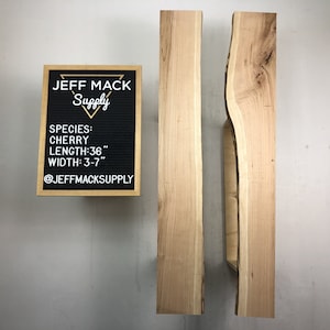 May include: Two pieces of cherry wood, each measuring 36 inches long and 3 to 7 inches wide. The wood has a natural live edge and is ready for woodworking projects.