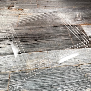 Peut inclure: Quatre feuilles d'acrylique transparentes empilées les unes sur les autres sur une surface en bois.