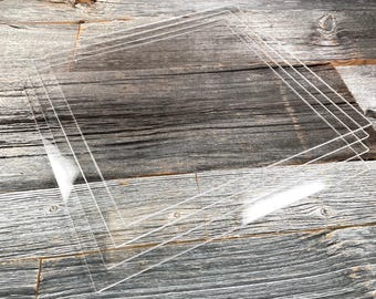 May include: Four clear acrylic sheets stacked on top of each other on a wooden surface.