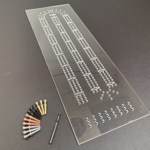 May include: A clear acrylic board with rows of holes for inserting metal pins. The board is accompanied by a set of metal pins in various colors, including gold, silver, copper, and black. A drill bit is also included.