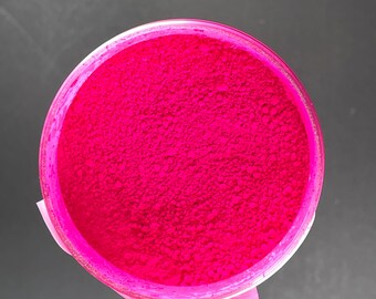 May include: A close-up view of a small container filled with bright pink powder. The powder is fine and evenly distributed throughout the container.