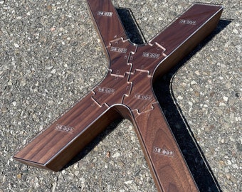 May include: A wooden puzzle in the shape of an X with a brown stain finish. The puzzle has 10 pieces with letters A through J and numbers 08-009 on each piece.