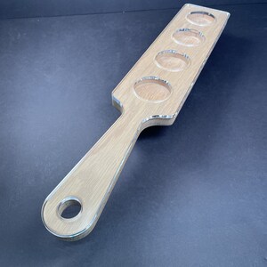 May include: A wooden serving tray with a handle and five clear circular cutouts. The tray is light brown and has a smooth finish.