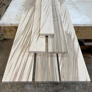 Peut inclure: Plusieurs planches de bois non finies avec des motifs de grain naturels. Les planches varient en largeur et en longueur, affichant des tons de bois clairs et foncés. Certaines planches présentent des marques linéaires, peut-être d'une scie. Le bois semble prêt pour la construction ou les projets de menuiserie.