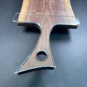 May include: A wooden cutting board with a unique, curved handle and a hole in the center. The board is made of walnut wood and has a natural finish.