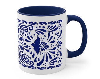 May include: White ceramic mug with a navy blue interior and handle. The exterior features a detailed blue floral and bird design. A decorative coffee mug for hot beverages.