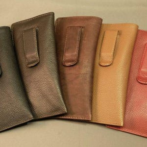 May include: Five leather eyeglass cases in different colors: dark green, brown, brown, tan, and red. Each case has a leather flap with a snap closure and a belt clip.