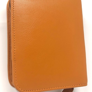 Könnte beinhalten: Eine braune Ledertasche mit Reißverschluss und Nähten an den Rändern.