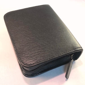 May include: A black leather zipped case with a textured surface.