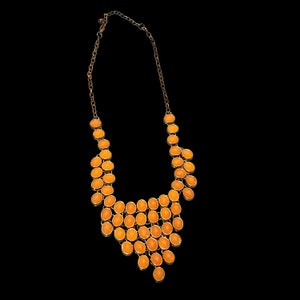 May include: A gold chain necklace with a cascading design of orange oval-shaped stones.