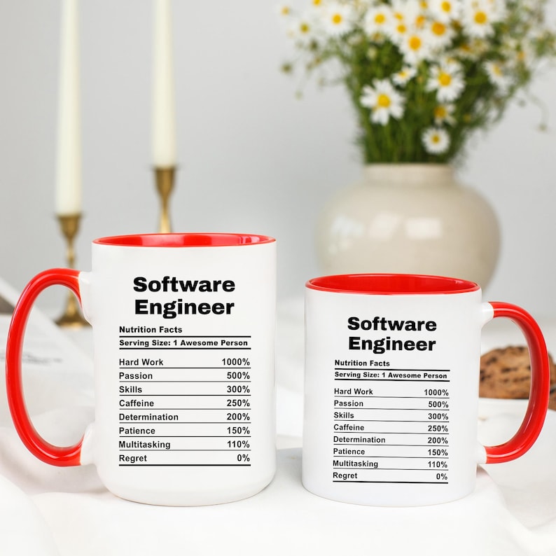 May include: Two white ceramic mugs with red interiors and handles. The mugs have the text "Software Engineer" and a "Nutrition Facts" label with percentages for hard work, passion, skills, caffeine, determination, patience, multitasking, and regret.
