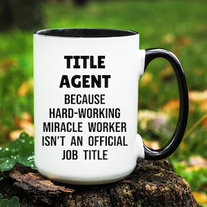 May include: White ceramic mug with a black interior and handle. The mug features the text "TITLE AGENT BECAUSE HARD-WORKING MIRACLE WORKER ISN'T AN OFFICIAL JOB TITLE" in bold black letters.