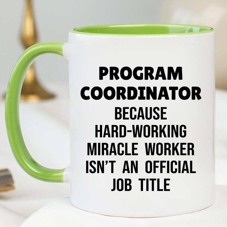 May include: White ceramic mug with a green handle and interior. The mug features the text "PROGRAM COORDINATOR BECAUSE HARD-WORKING MIRACLE WORKER ISN'T AN OFFICIAL JOB TITLE" in black, bold font.