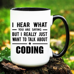 May include: White ceramic mug with a black interior and handle. The mug features the text "I HEAR WHAT YOU ARE SAYING BUT I REALLY JUST WANT TO TALK ABOUT CODING" in black, perfect for programmers and coders.