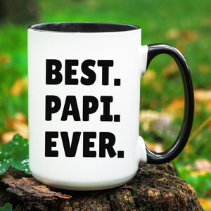 May include: White ceramic mug with a black rim and handle. The mug has the text "BEST. PAPI. EVER." printed in black.