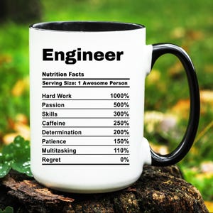 May include: White ceramic mug with a black handle. The mug has a black rim and features a graphic of a nutrition facts label for an "Engineer". The label lists the percentage of different qualities, such as hard work, passion, skills, caffeine, determination, patience, multitasking, and regret.