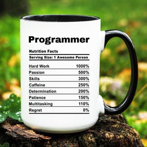May include: White ceramic mug with a black handle. The mug has a black rim and features a graphic of a nutrition facts label for a "Programmer". The label lists the percentage of different qualities, such as "Hard Work", "Passion", "Skills", "Caffeine", "Determination", "Patience", "Multitasking", and "Regret".