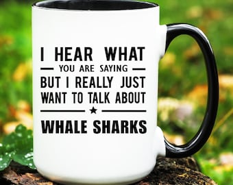 May include: White ceramic mug with a black handle and rim. The mug features the text "I HEAR WHAT - YOU ARE SAYING - BUT I REALLY JUST WANT TO TALK ABOUT WHALE SHARKS" in black, with a star graphic.