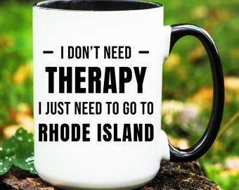 May include: White ceramic mug with a black interior and handle. The mug features the text "I DON'T NEED THERAPY I JUST NEED TO GO TO RHODE ISLAND" in bold black letters.